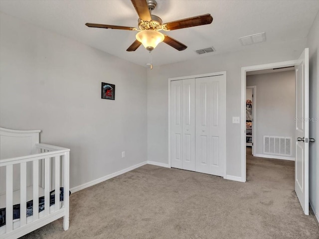 unfurnished bedroom featuring ceiling fan, a closet, and light colored carpet