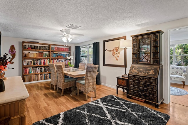 dining area featuring hardwood / wood-style flooring, ceiling fan, and a textured ceiling