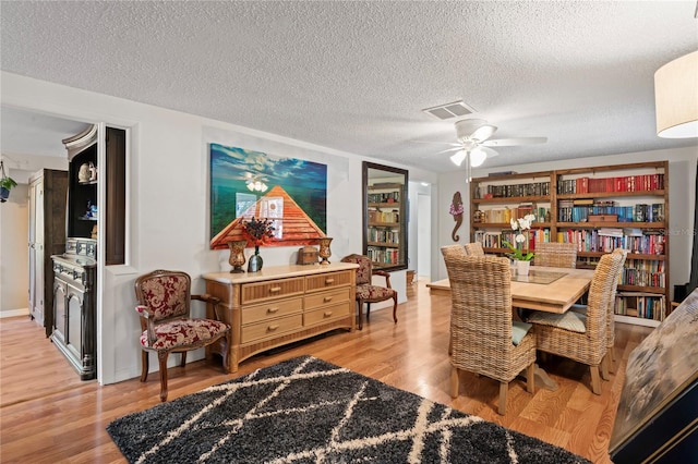 dining area with a textured ceiling, light hardwood / wood-style floors, and ceiling fan