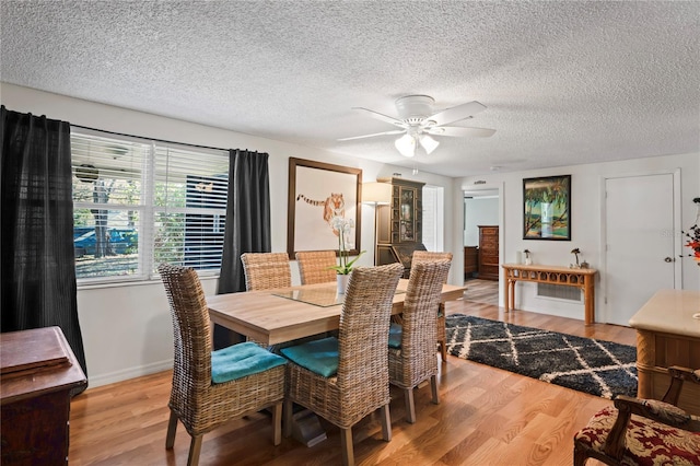 dining room featuring wood-type flooring, a textured ceiling, and ceiling fan