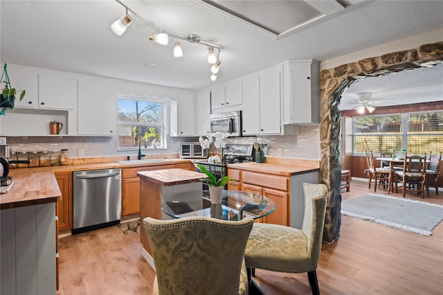 kitchen featuring stainless steel appliances, white cabinetry, ceiling fan, and butcher block counters