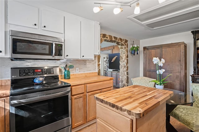 kitchen with backsplash, white cabinets, a kitchen island, butcher block counters, and stainless steel appliances