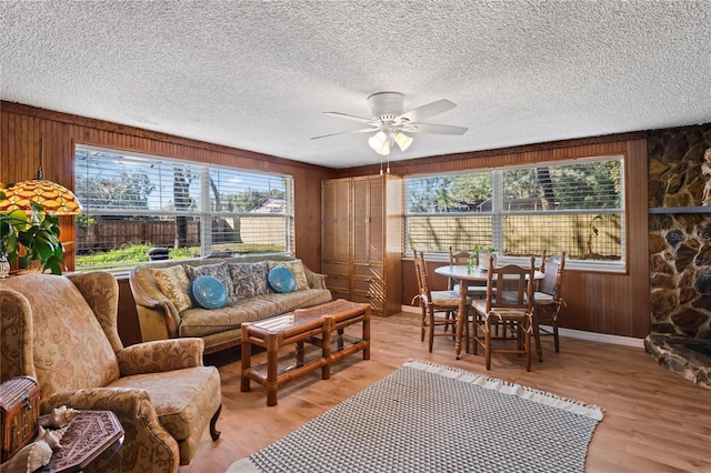 living room with ceiling fan, wood walls, and light hardwood / wood-style floors