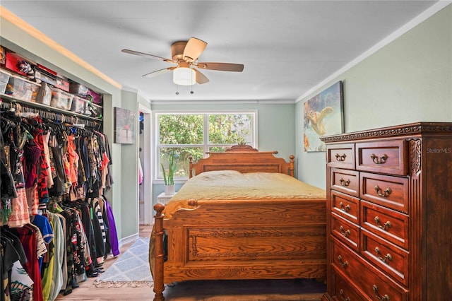 bedroom with ceiling fan, light wood-type flooring, crown molding, and a closet