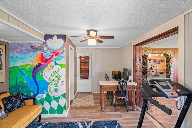 office space featuring ceiling fan, wood walls, wood-type flooring, and a textured ceiling