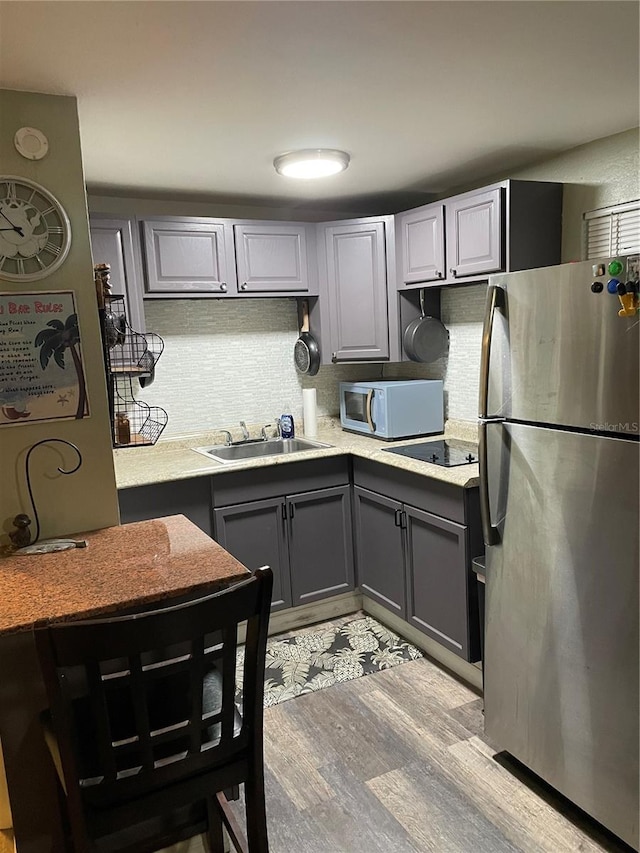 kitchen with gray cabinetry, stainless steel fridge, and sink