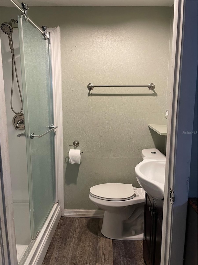 bathroom featuring wood-type flooring, vanity, toilet, and an enclosed shower