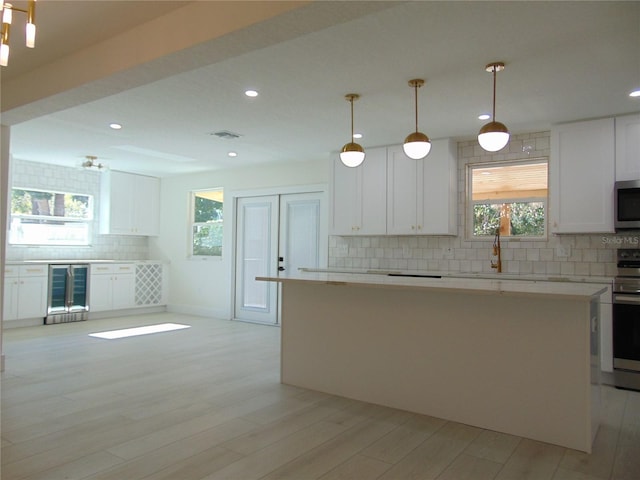 kitchen with backsplash, white cabinets, stainless steel appliances, and decorative light fixtures