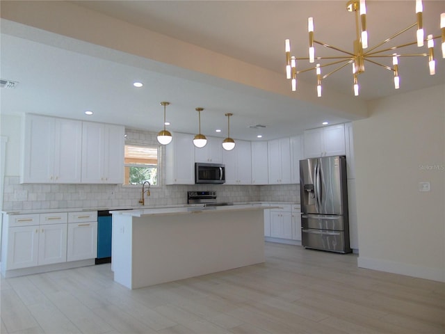 kitchen featuring white cabinets, decorative light fixtures, a center island, and appliances with stainless steel finishes