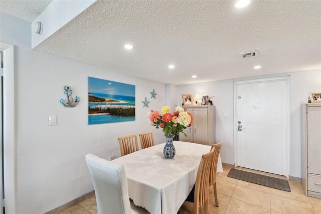 tiled dining room featuring a textured ceiling