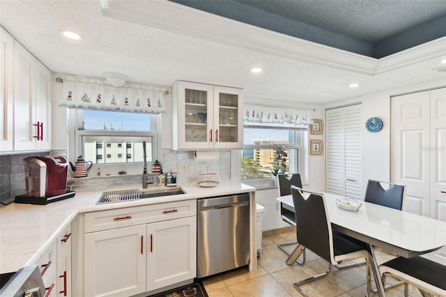 kitchen featuring white cabinetry, stainless steel dishwasher, decorative backsplash, and a textured ceiling