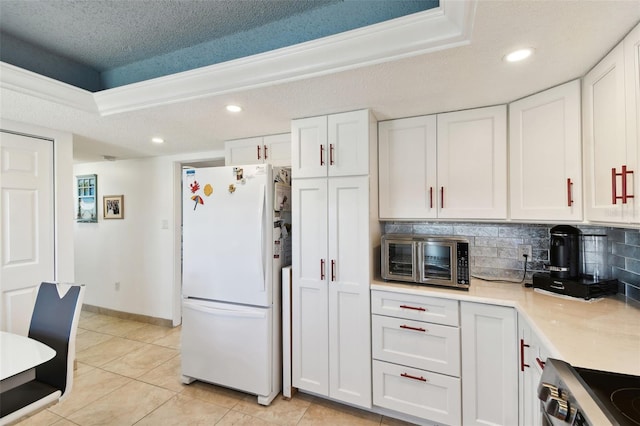 kitchen featuring a textured ceiling, white cabinets, and white refrigerator