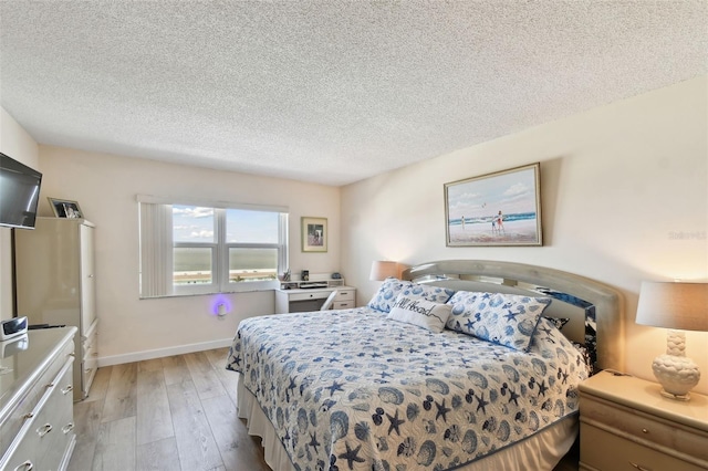 bedroom with light hardwood / wood-style floors and a textured ceiling