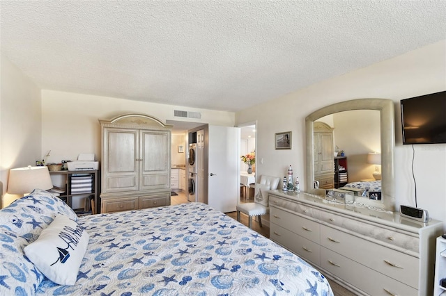 bedroom featuring stacked washing maching and dryer and a textured ceiling