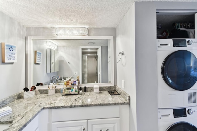 bathroom featuring vanity, a textured ceiling, and stacked washing maching and dryer