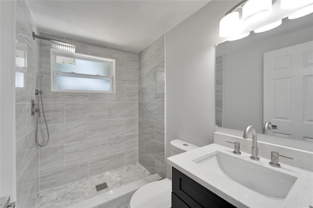 bathroom featuring vanity, toilet, and tiled shower