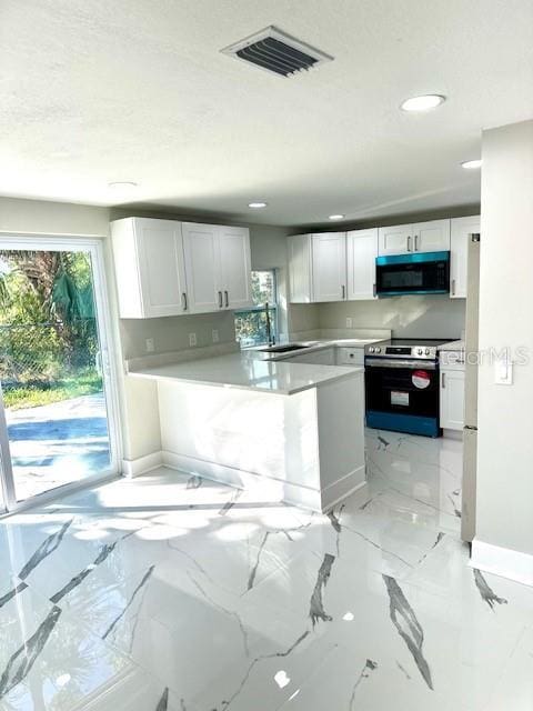 kitchen with white cabinetry, stainless steel electric range oven, and sink