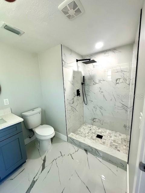 bathroom featuring tiled shower, vanity, and toilet