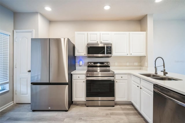 kitchen with white cabinets, sink, light wood-type flooring, and stainless steel appliances