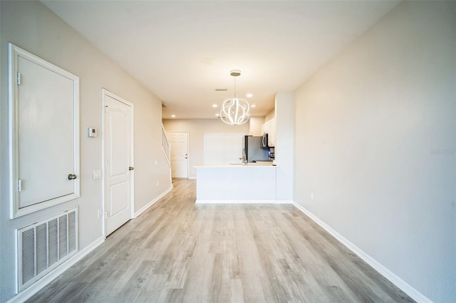 unfurnished dining area with light hardwood / wood-style flooring and a notable chandelier