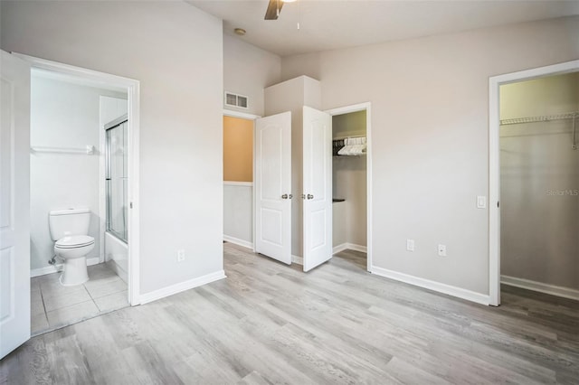 unfurnished bedroom with ensuite bath, ceiling fan, lofted ceiling, and light wood-type flooring