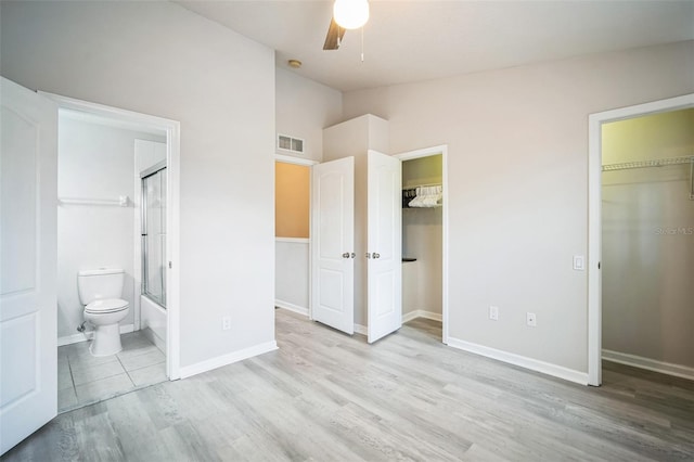 unfurnished bedroom featuring ensuite bathroom, ceiling fan, light hardwood / wood-style floors, and vaulted ceiling