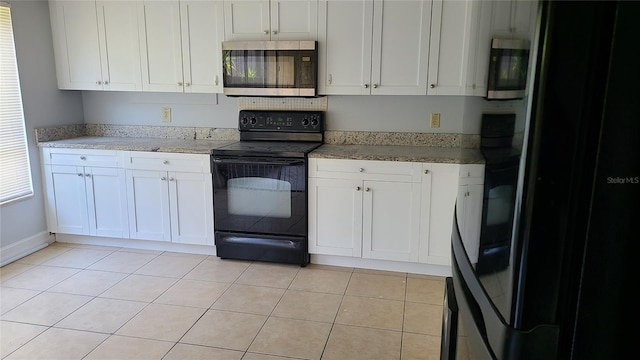 kitchen with light stone counters, white cabinets, light tile patterned floors, and black appliances