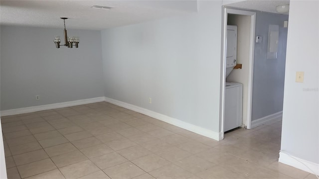 unfurnished room featuring electric panel, a chandelier, and stacked washer / dryer