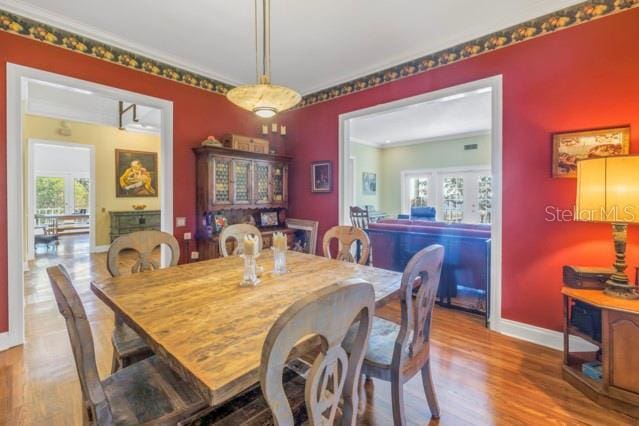 dining space with wood-type flooring and crown molding