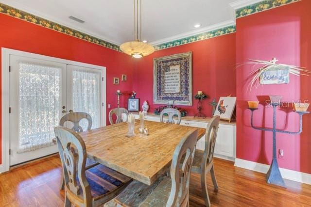 dining space featuring french doors, light hardwood / wood-style flooring, and crown molding