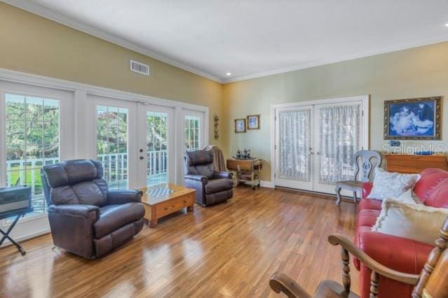 living area featuring hardwood / wood-style floors, crown molding, and french doors