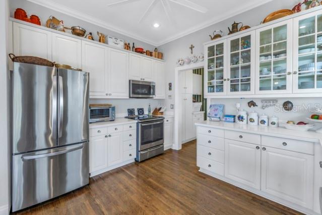 kitchen featuring dark hardwood / wood-style flooring, stainless steel appliances, white cabinetry, and ornamental molding