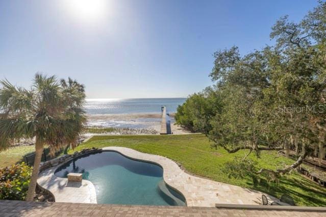 view of pool with a lawn, a patio area, and a water view