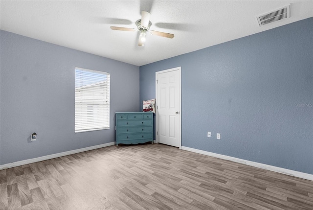 unfurnished room featuring ceiling fan, wood finished floors, visible vents, and baseboards