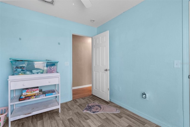 bedroom featuring ceiling fan, visible vents, baseboards, and wood finished floors