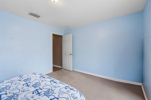 unfurnished bedroom with visible vents, baseboards, light colored carpet, and a textured ceiling