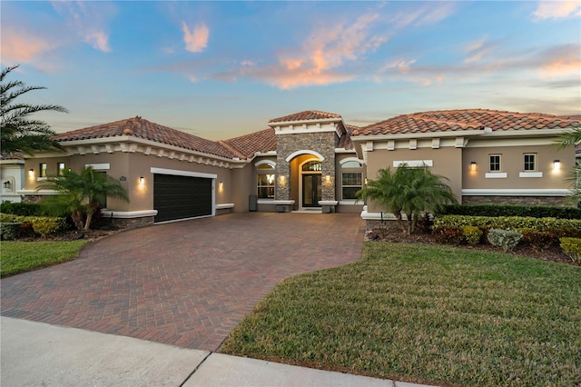 mediterranean / spanish home featuring a garage and a lawn