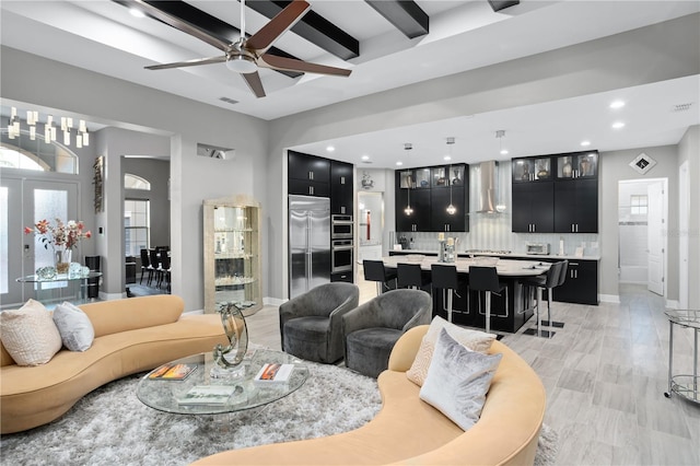 living room with a wealth of natural light, ceiling fan, and beamed ceiling