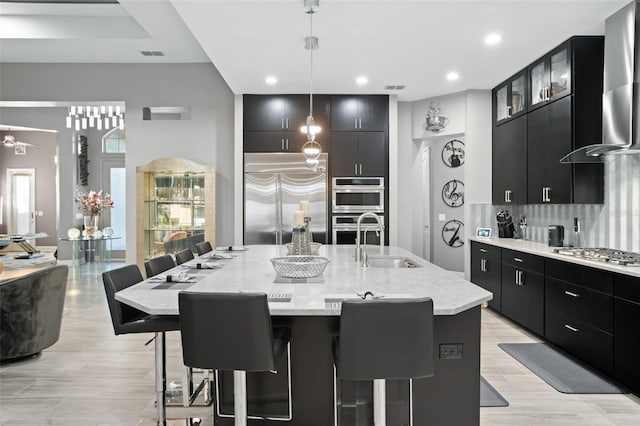 kitchen featuring stainless steel appliances, sink, a kitchen bar, a center island with sink, and pendant lighting