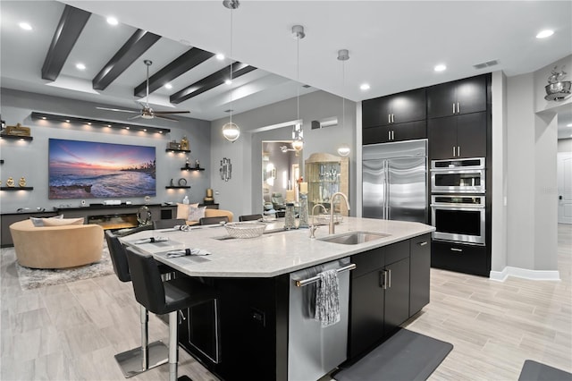 kitchen with hanging light fixtures, stainless steel appliances, ceiling fan, a spacious island, and sink