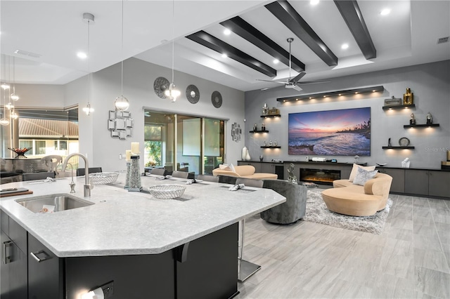 kitchen with pendant lighting, a breakfast bar, a large island with sink, ceiling fan, and sink