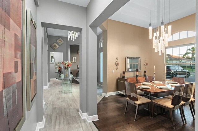 dining area featuring a towering ceiling, a chandelier, and wood-type flooring