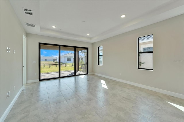 spare room featuring a tray ceiling and light tile patterned floors