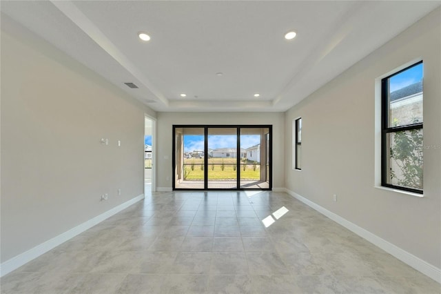 tiled spare room with a tray ceiling