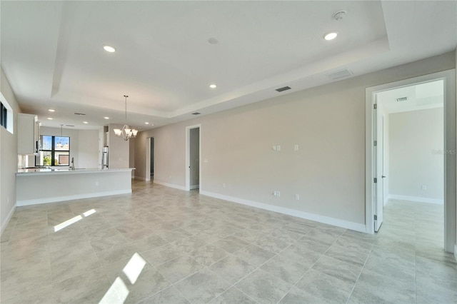 unfurnished living room with a notable chandelier and a tray ceiling