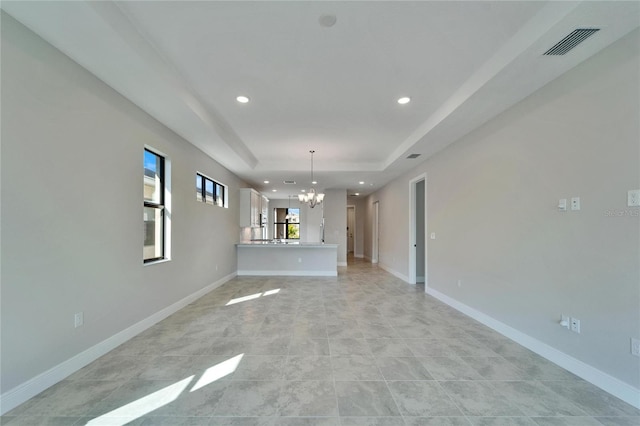 unfurnished living room with a raised ceiling and a notable chandelier