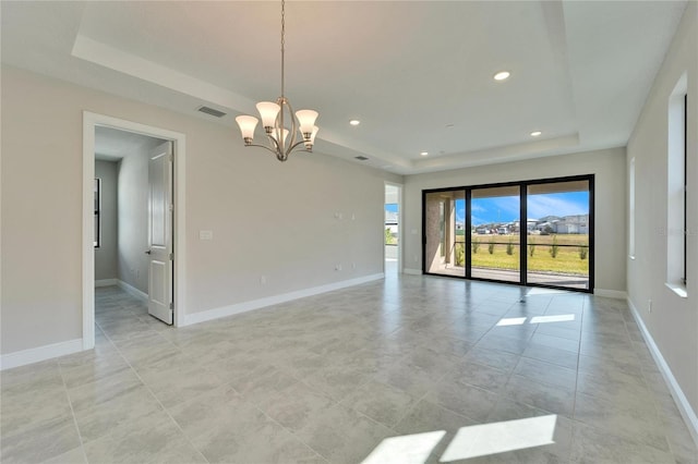 spare room featuring an inviting chandelier and a tray ceiling