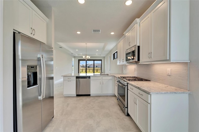 kitchen featuring stainless steel appliances, white cabinets, hanging light fixtures, and kitchen peninsula