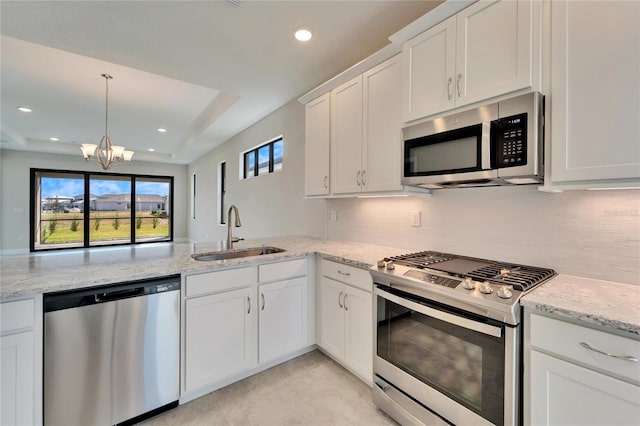 kitchen featuring stainless steel appliances, sink, white cabinetry, light stone counters, and a chandelier