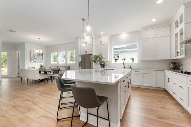 kitchen featuring high end refrigerator, an inviting chandelier, white cabinets, a center island, and light hardwood / wood-style floors